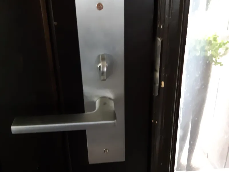 Commercial mortise lever lock installed on a black door