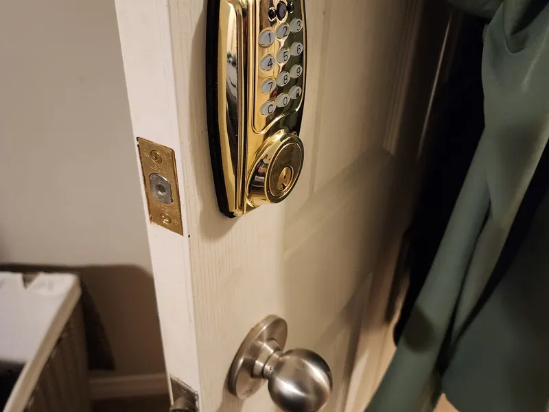 Gold electronic keypad deadbolt installed on a white door