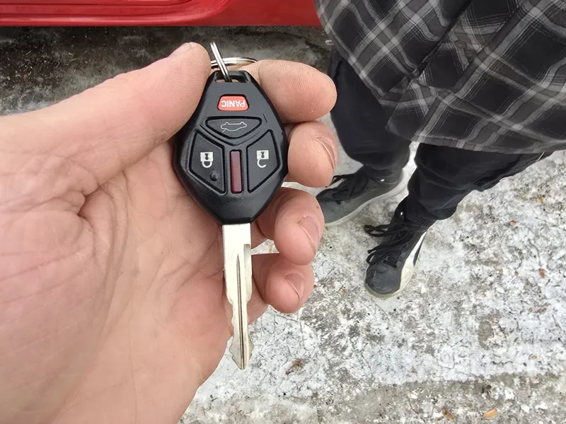 Mitsubishi key fob with a red car in the background