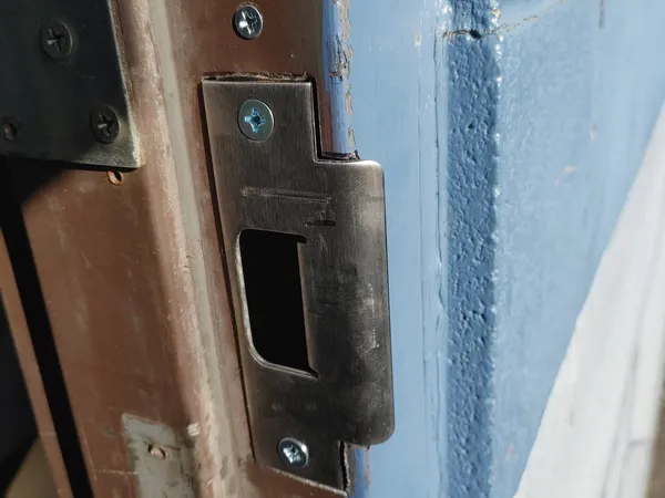 Strike plate installed on a blue door frame