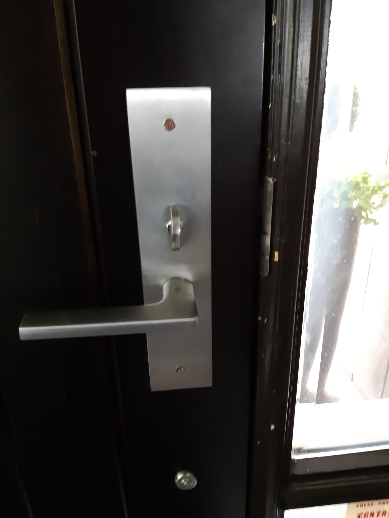 Commercial mortise lever lock installed on a black door