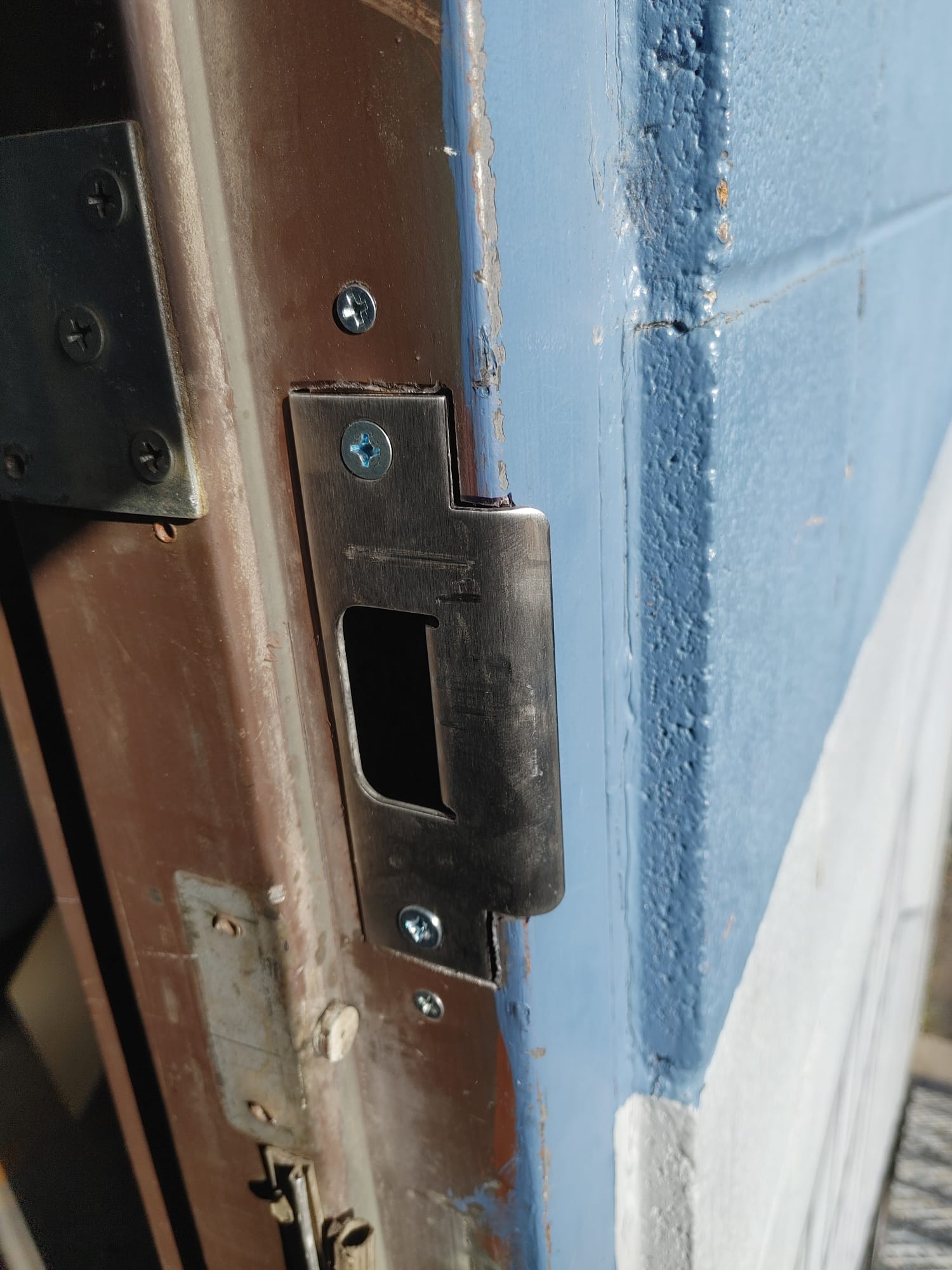 Strike plate installed on a blue door frame
