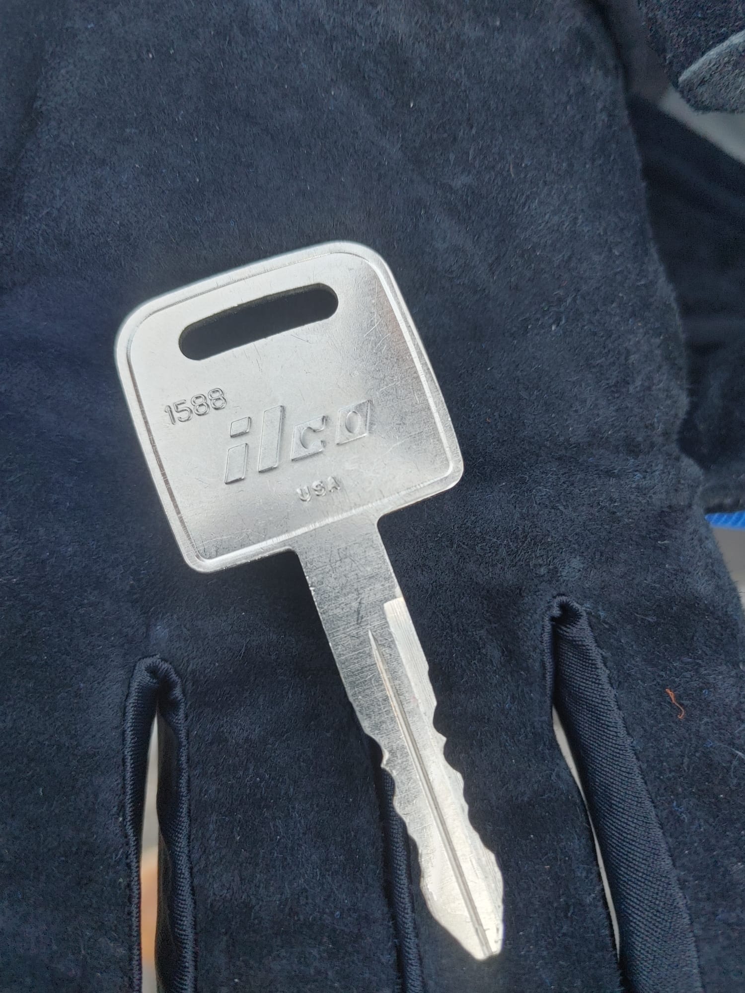 ILCO 1588 key blank on a gloved hand