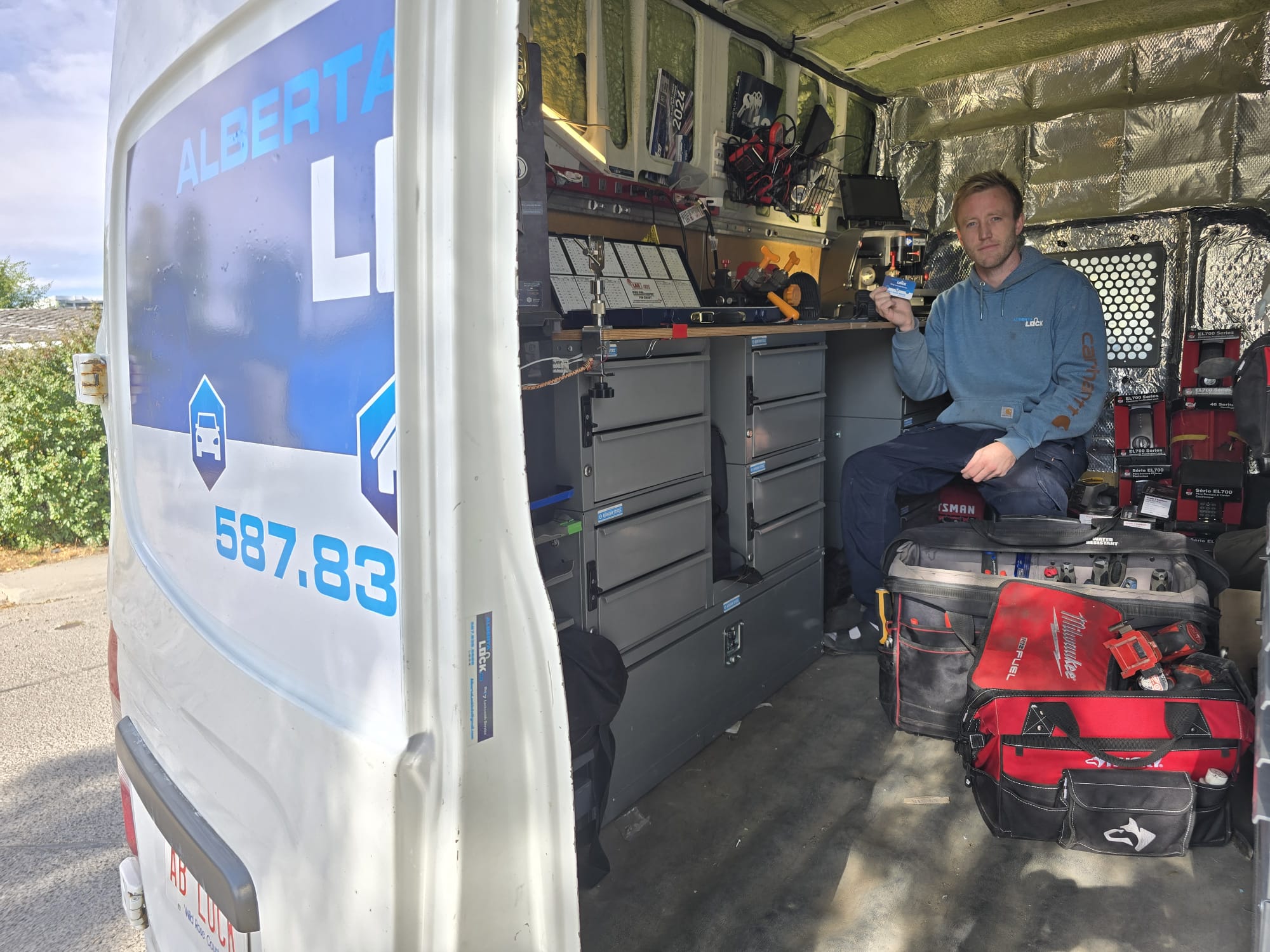 Locksmith technician inside the van surrounded by labelled tool drawers