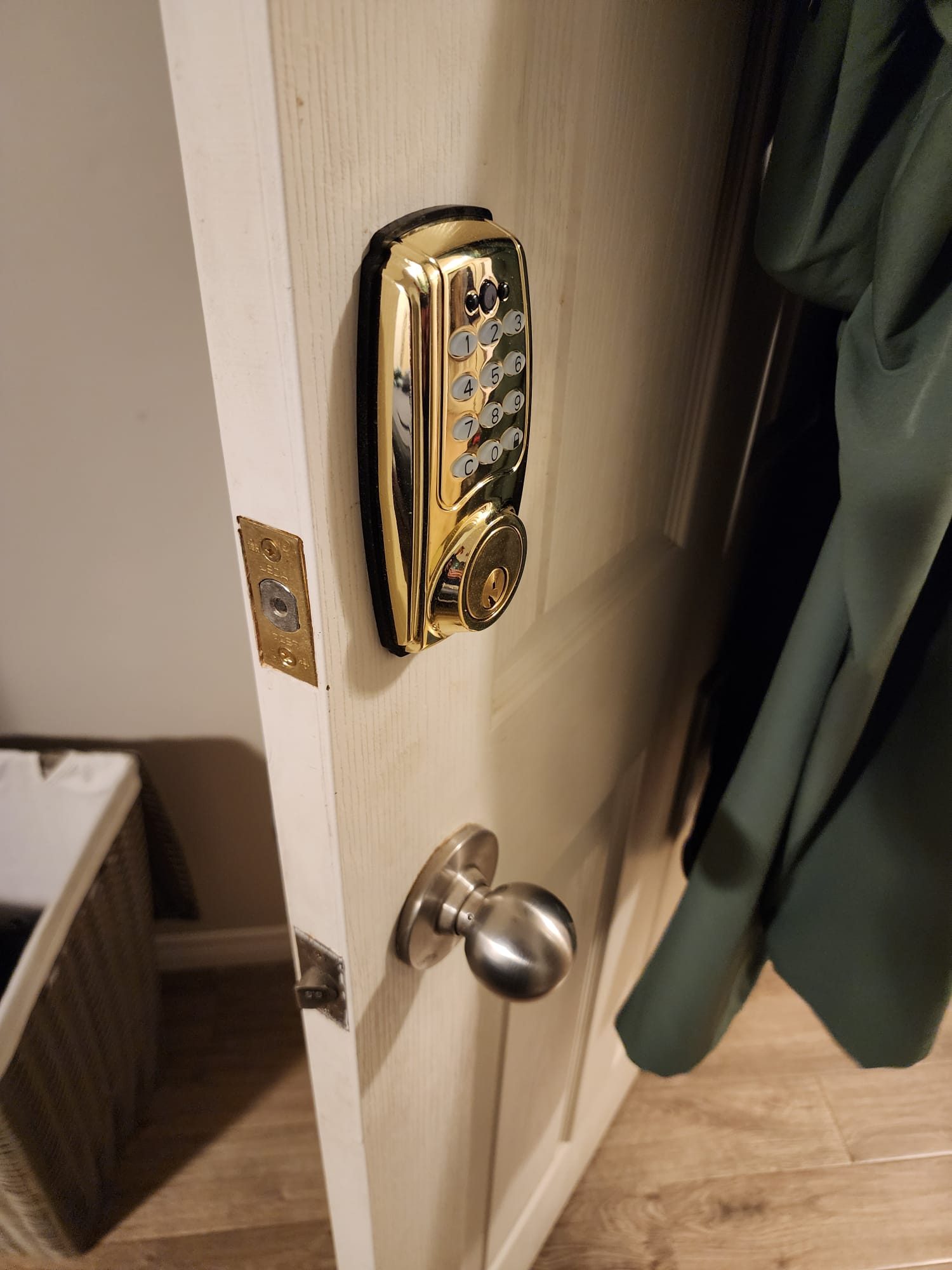 Gold electronic keypad deadbolt installed on a white door